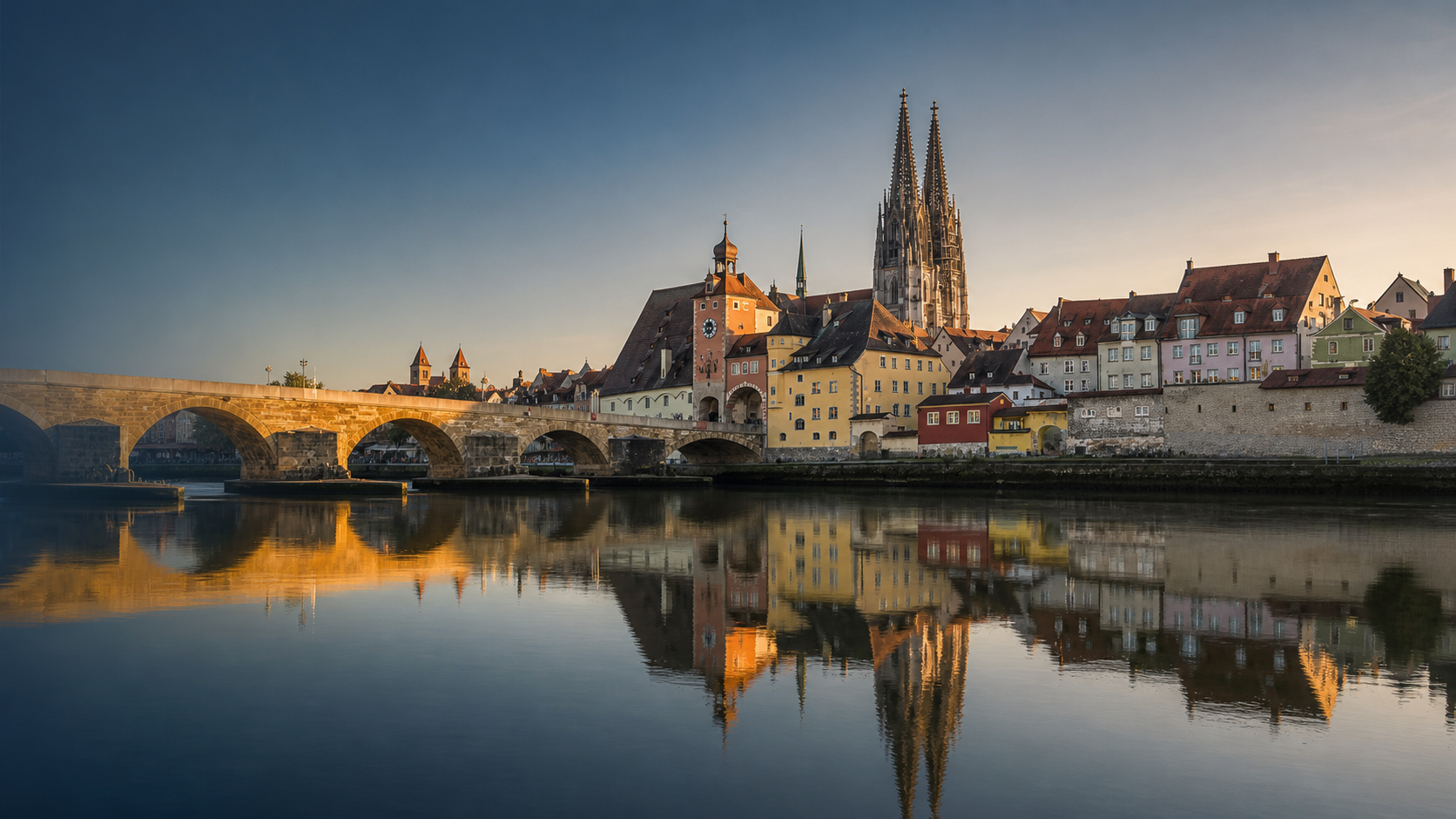 Regensburger Altstadt mit Steinerner Brücke und Dom, gespiegelt in der Donau im Abendlicht